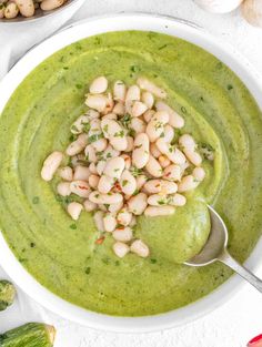 a white bowl filled with green soup and beans