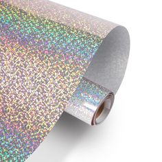 multicolored glitter wrapping paper is shown on a white background with a roll of tape