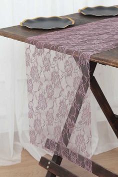 a table with two plates on top of it and a purple lace runner over the edge