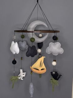 a wind chime hanging from the side of a wall next to a moon and clouds