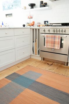 a kitchen with an oven, dishwasher and rug on the floor in front of it