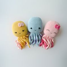 three crocheted octopus stuffed animals sitting next to each other on a white surface