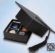 an open graduation cap sitting on top of a box filled with candies and chocolates