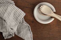 a wooden spoon sitting on top of a white bowl next to a striped dish cloth