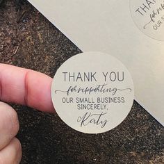 a hand holding a thank you sticker in front of a white envelope that says, thank you for supporting our small business sincely