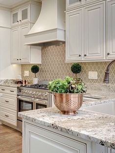 a kitchen with white cabinets and marble counter tops