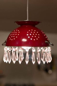 a red light hanging from a ceiling with crystal drops on it's glass beads