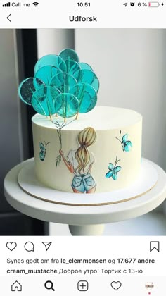 a white cake with blue frosting and flowers on the top is sitting on a stand