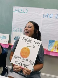 a woman holding up a sign that says orange you glad that god loves you in front of her