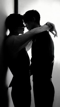 black and white photograph of two people embracing each other in front of a window with blinds