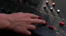 a hand is pressing buttons on a sound mixing console