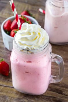 strawberry milkshake with whipped cream and strawberries in the background on a wooden table