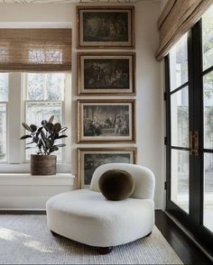 a living room with pictures on the wall and a chair in front of a window