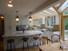 a kitchen with white cabinets and counter tops next to a wooden table in front of an open window