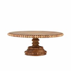 a wooden cake stand with beads on it's sides and an oval base,