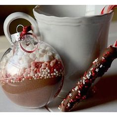 a glass ornament filled with candy and sprinkles next to a cup