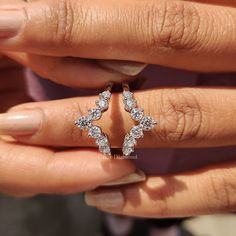 a woman's hand holding an open ring with three small diamonds on top of it