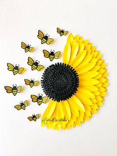 a sunflower made out of black and yellow paper is surrounded by bees on white background