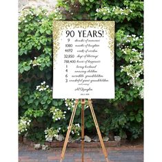 an easel with a sign that says 90 years on it in front of some bushes