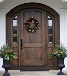 two large planters with wreaths on the front door