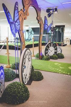 several clocks with different designs on them in an office lobby area, one has a butterfly clock and the other is a bicycle