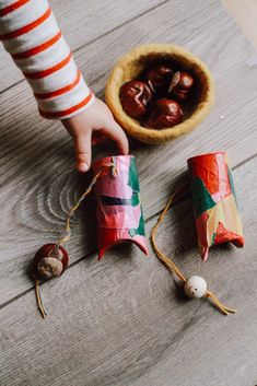 a small child reaching for some nuts in a bowl on the floor next to an ornament