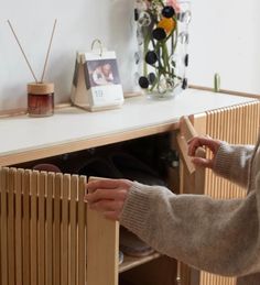 a woman is opening the radiator in front of a table with flowers on it