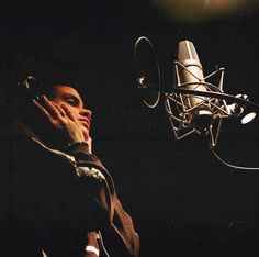 a man talking on a cell phone in front of a microphone