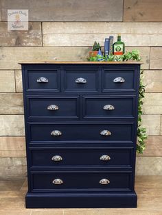 a blue dresser with brass handles and knobs on it's drawers in front of a brick wall