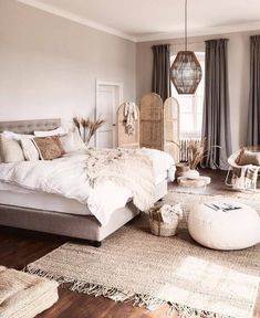 a bedroom with a large bed and lots of pillows on the floor in front of it