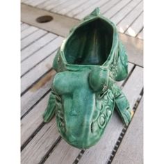 a green ceramic animal planter sitting on top of a wooden floor next to a drain