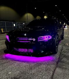 a black car with purple lights on it's hood and the front end is shown