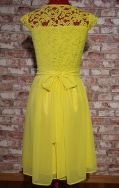 a yellow dress on a mannequin with a brick wall in the back ground