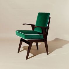 a green chair sitting on top of a white floor next to a wooden armrest