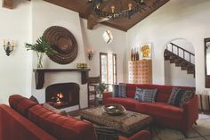 a living room with red couches and a fire place in the middle of it