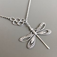 a silver dragonfly necklace with diamonds on it's back and wings hanging from the front