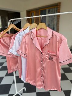 three pink and white shirts are hanging on a rack in front of a black and white checkered floor