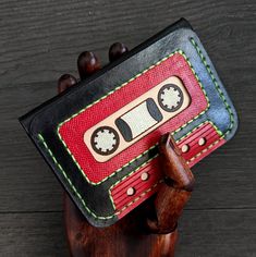 a red and black wallet with an old fashioned cassette tape recorder on it's side