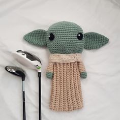 a crocheted baby yoda doll next to a golf club