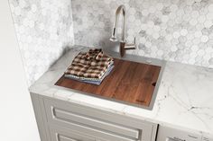 a kitchen counter with a cutting board on it next to a faucet and sink