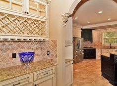 a large kitchen with marble counter tops and white cabinets, along with an arched doorway leading to the dining room