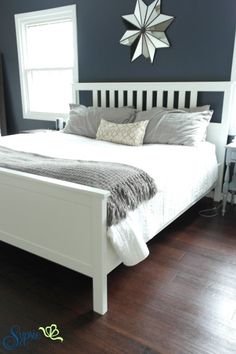 a white bed sitting on top of a hard wood floor next to a wall mounted clock