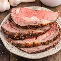 sliced meat sitting on top of a plate next to garlic