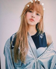 a woman with long hair wearing a jacket and flowers in her hair is posing for the camera