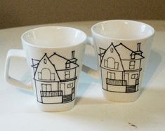 two coffee cups with houses drawn on them