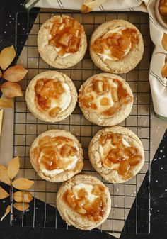 several small pies sitting on top of a cooling rack next to leaves and a napkin