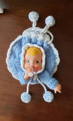 a baby doll wearing a blue hat and holding a pacifier in it's mouth