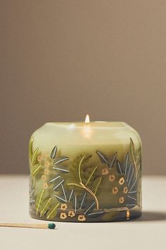 a lit candle sitting on top of a table next to a matchstick and glass container