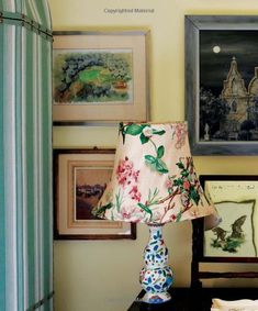 a lamp sitting on top of a wooden table next to pictures and framed art above it