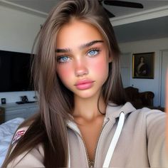 a woman with long brown hair and blue eyes is taking a selfie in her bedroom